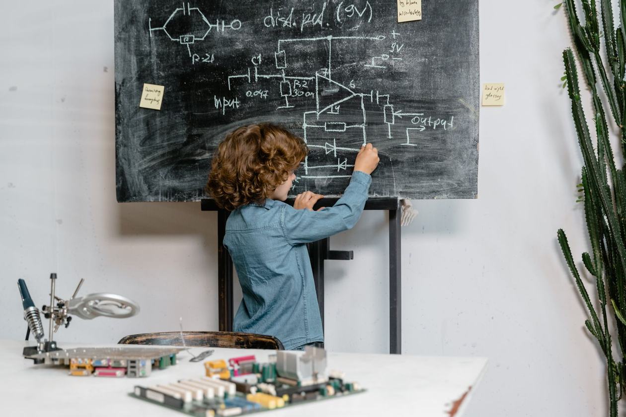 A young student writing equations on a chalkboard